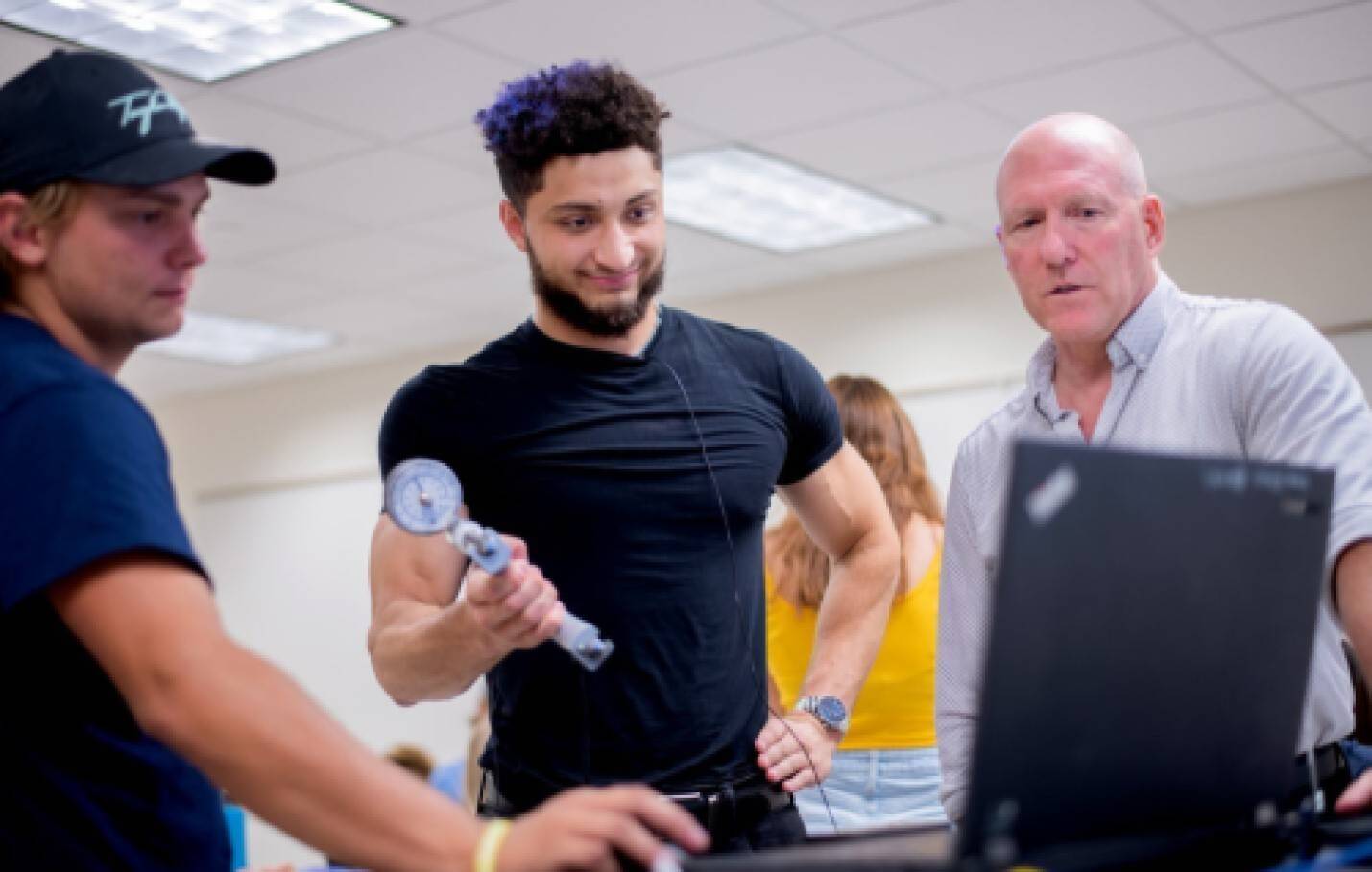 Professor working with students to explain exercise testing equipment.